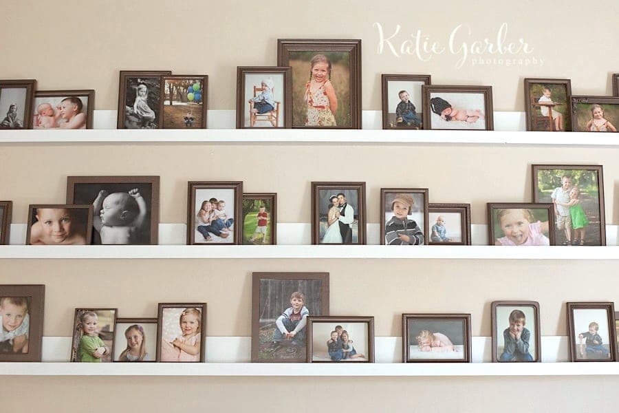 Long wooden gallery ledge shelf with leaning framed pictures