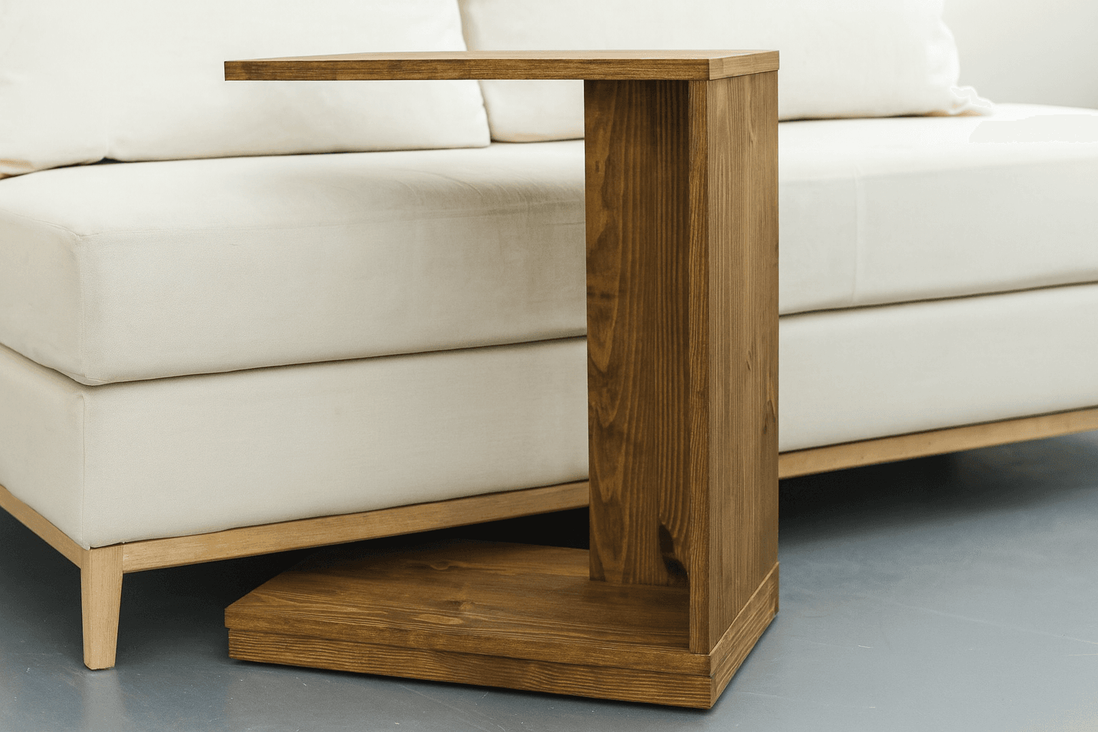 White C-shaped rolling end table positioned over a sofa edge