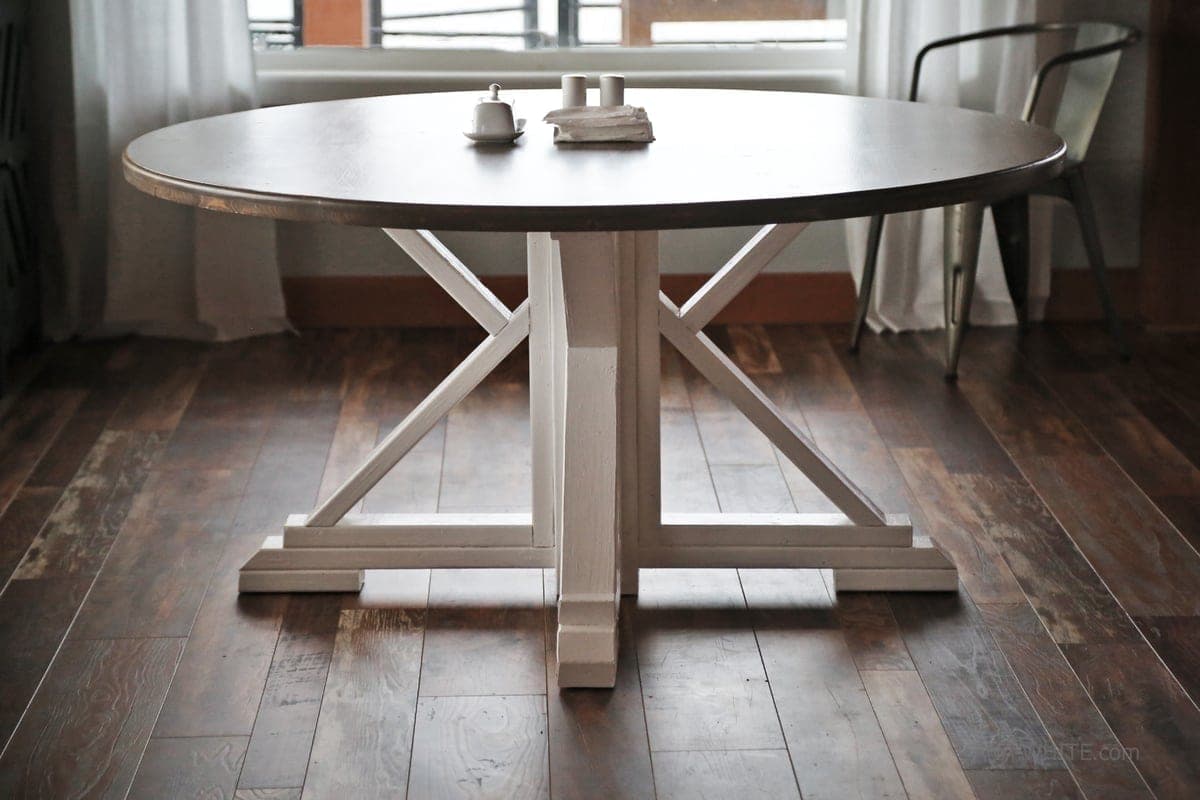 Round farmhouse dining table on a splayed four-leg pedestal base