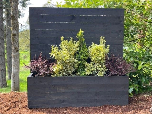 Tall cedar privacy screen rising from a planter box base on a patio