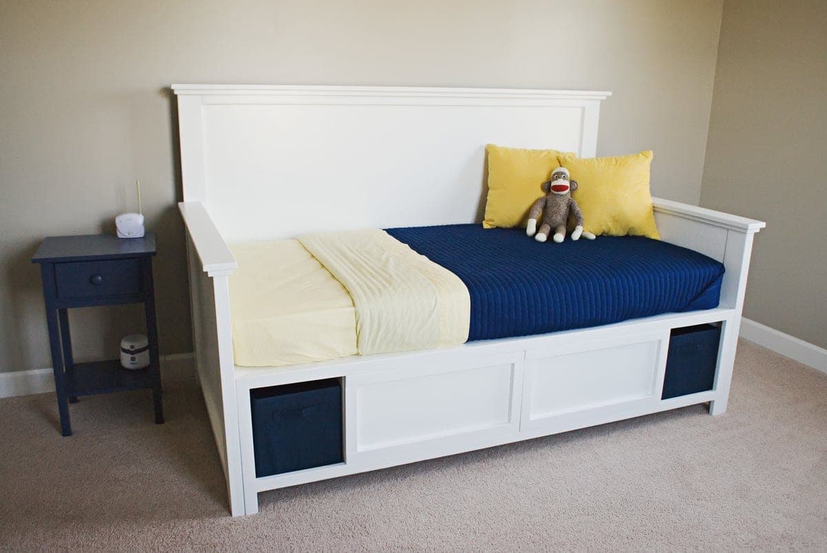 Storage daybed with a paneled back and two arms over drawer storage
