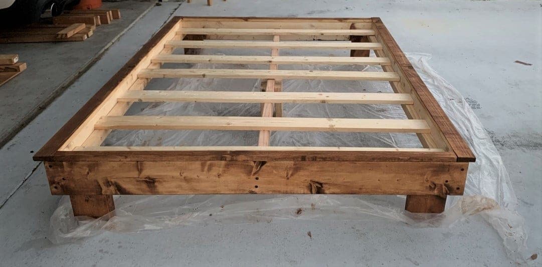 Low modern platform bed frame in stained construction lumber with short legs