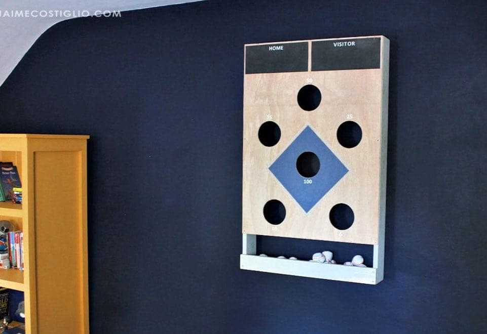 A wall-hung bean bag toss board with a baseball diamond hole pattern