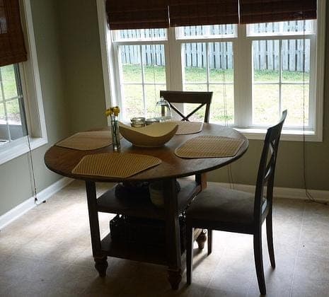 Round dining table with two open storage shelves built into the base