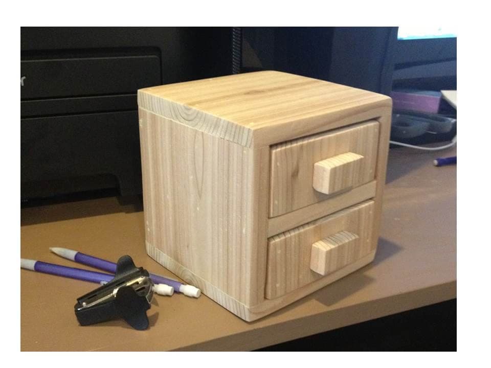 Tiny two-drawer cedar storage cube on a desk