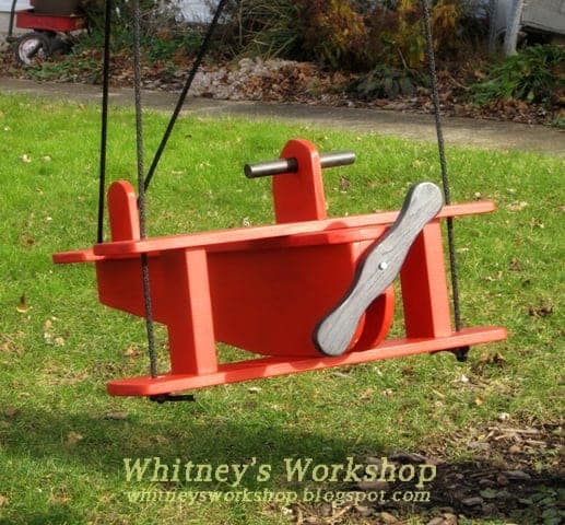 Child's wooden airplane swing hanging from rope