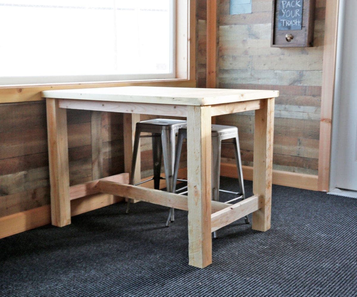 Counter height farmhouse table with a plywood top framed in trim, sized for four stools