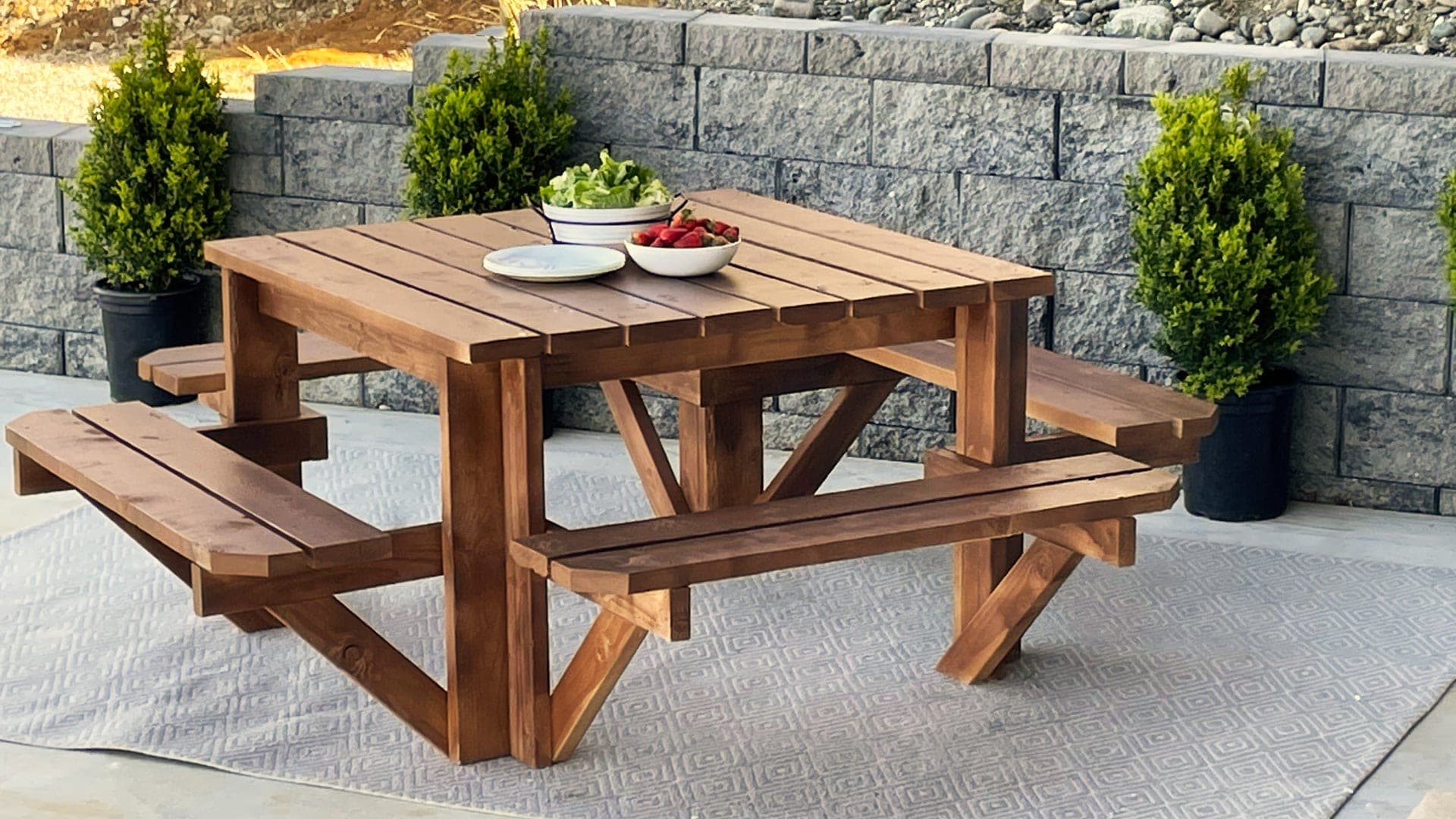 Square wooden picnic table with attached seats on all four sides