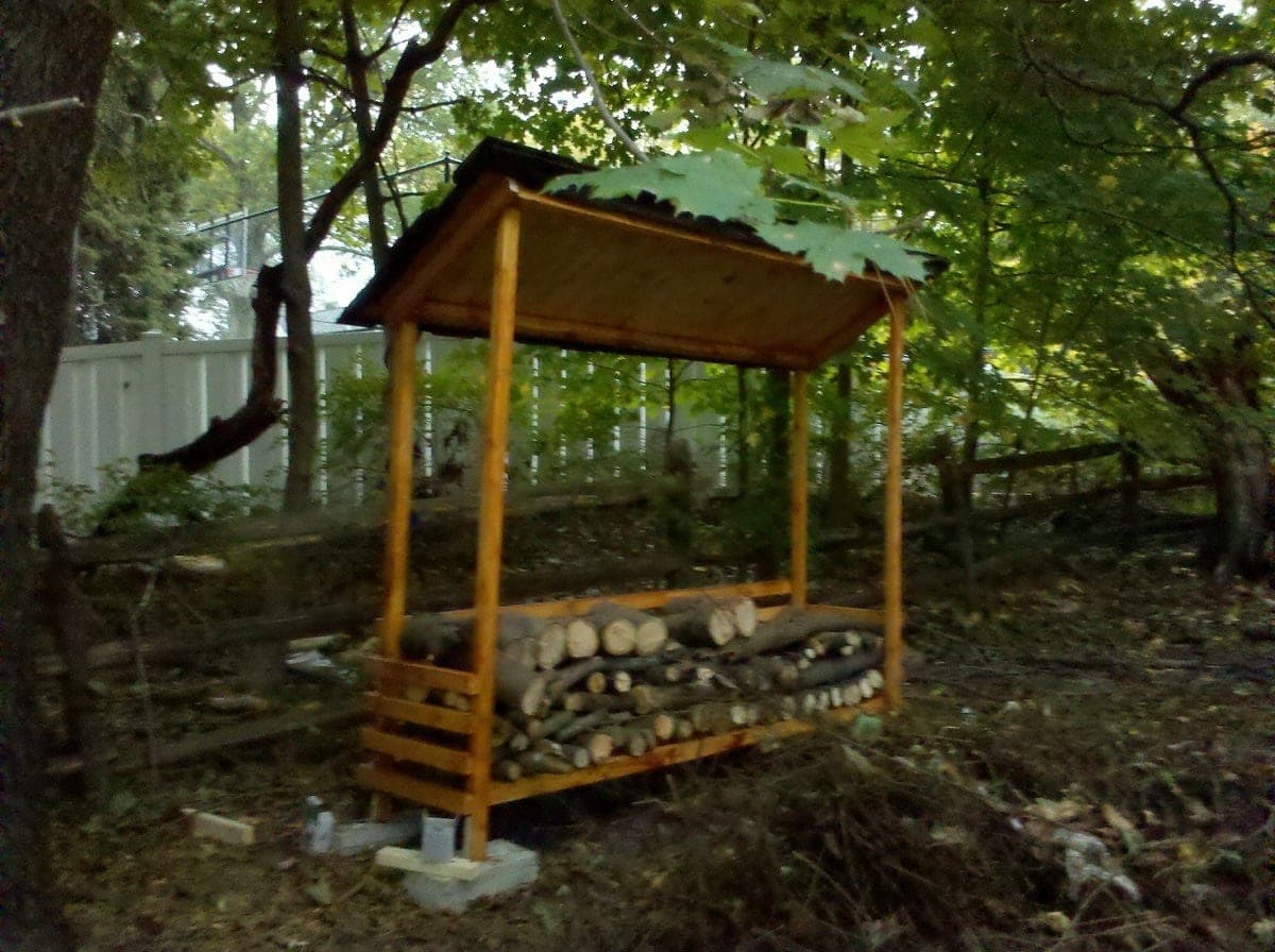 Open-sided lean-to firewood shed with a shingled roof