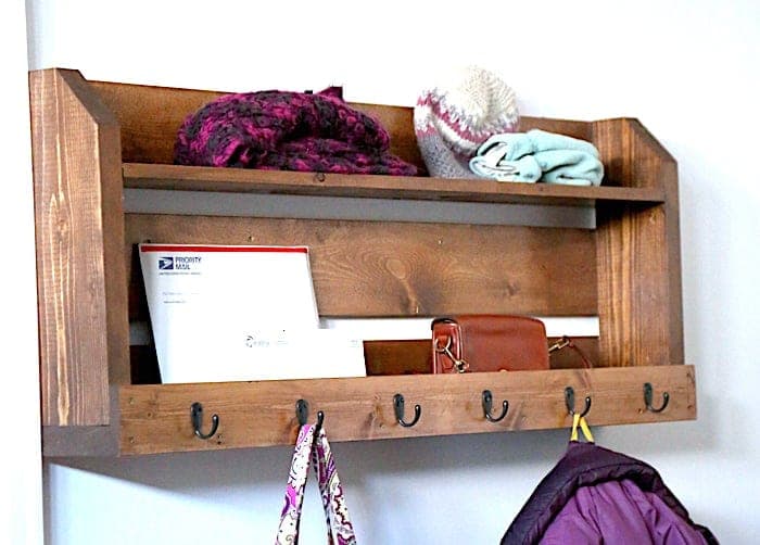 A small wall-mounted coat rack with a shelf, slatted back, and six hooks