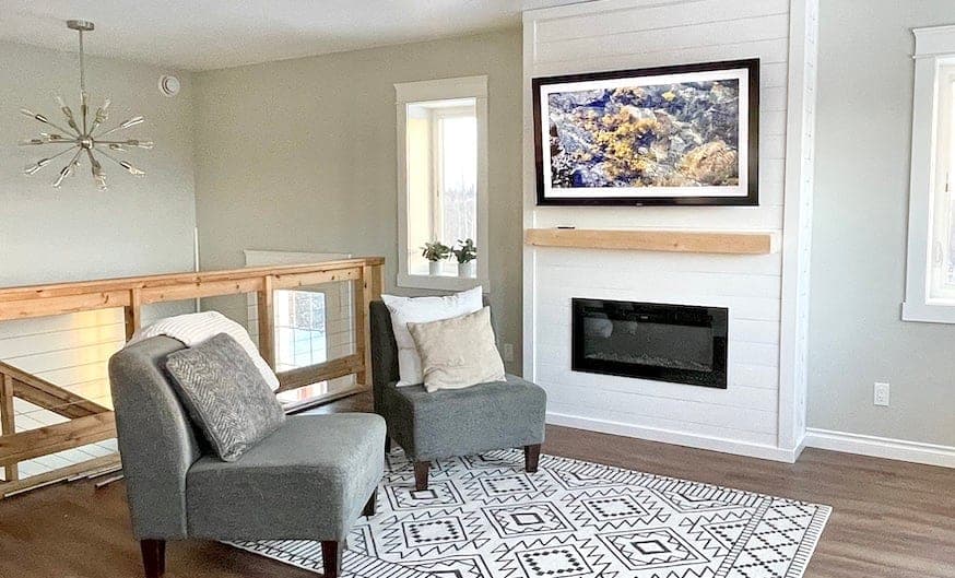 Floor-to-ceiling white shiplap fireplace surround with wood beam mantle and TV above