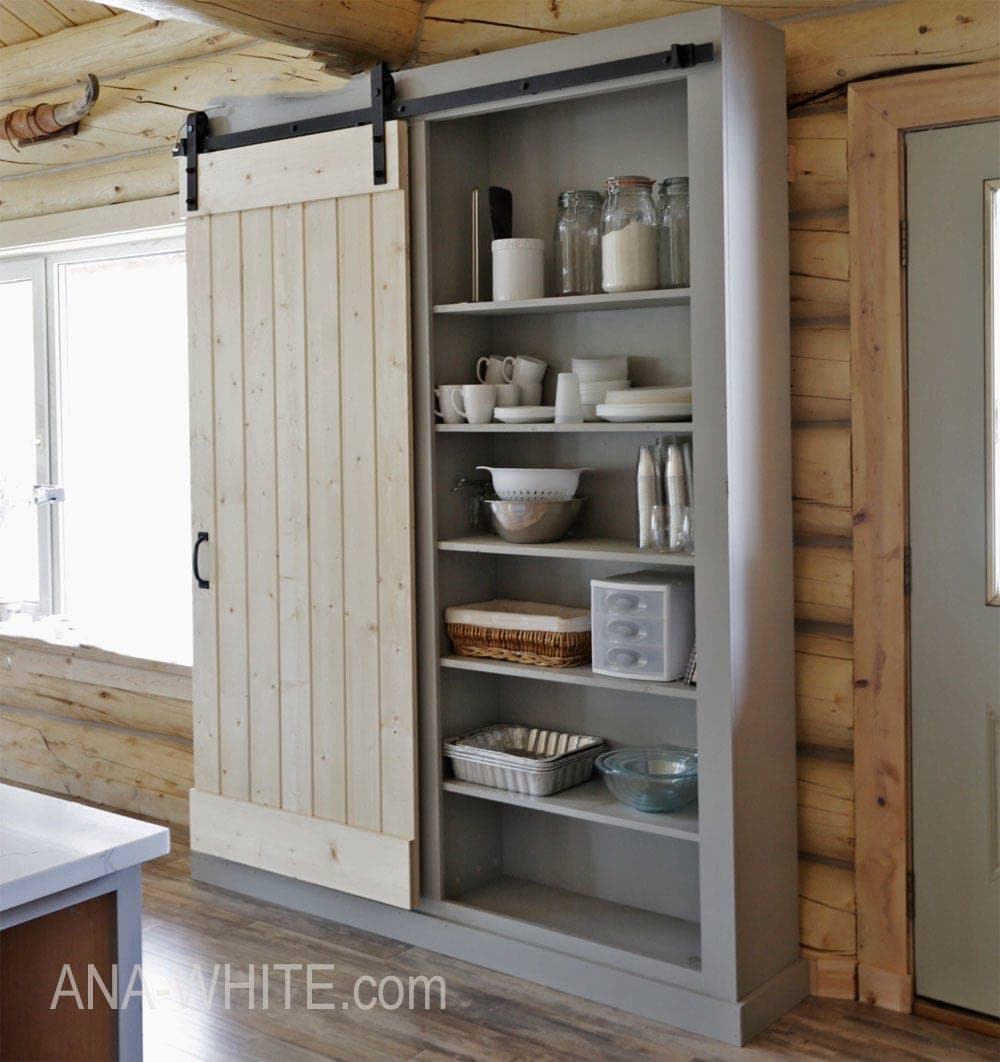 A tall pantry cabinet with a sliding tongue-and-groove barn door on a track