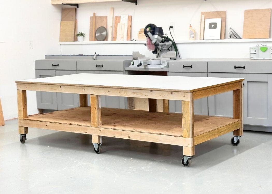 Large 4x8 rolling work table with 2x4 frame, plywood lower shelf, and white melamine top