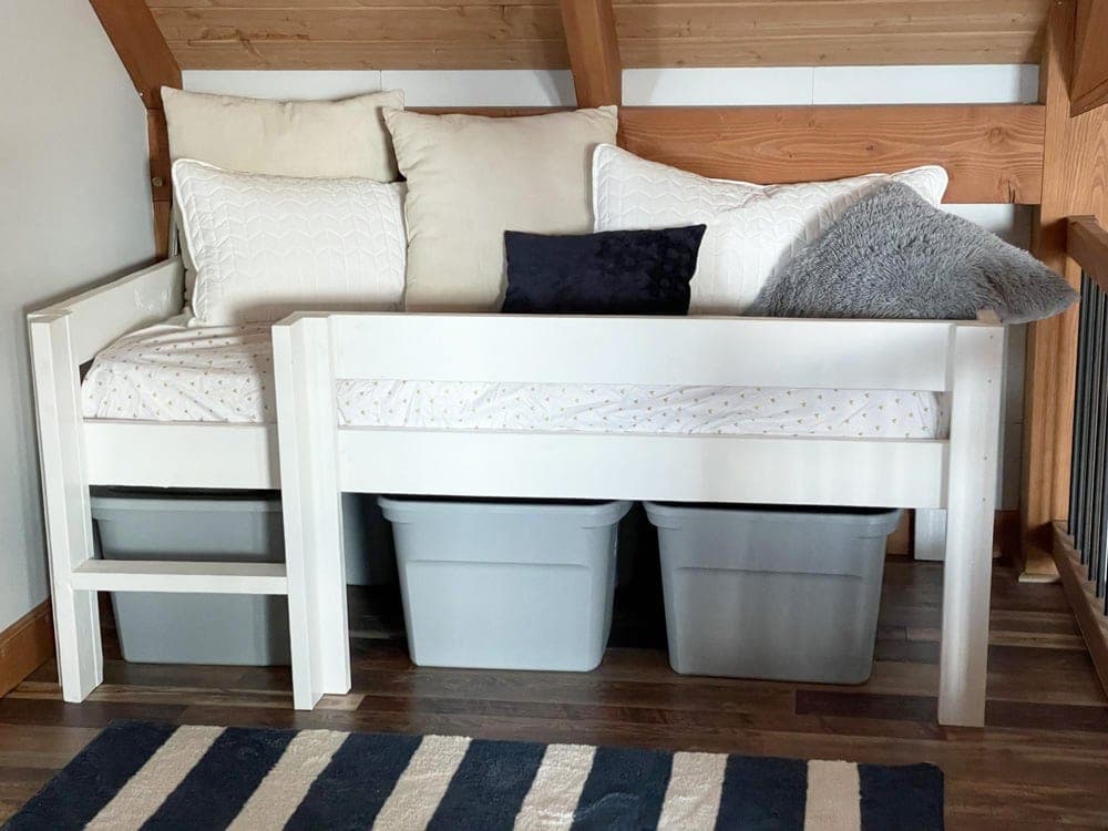Low twin loft bed in natural wood with ladder and storage totes underneath