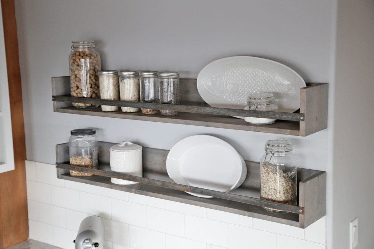 A simple open wall shelf with a thin metal bar across the front edge