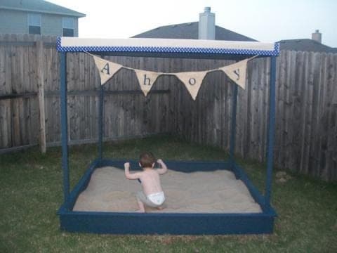 Large wooden sandbox with a canopy frame over the top