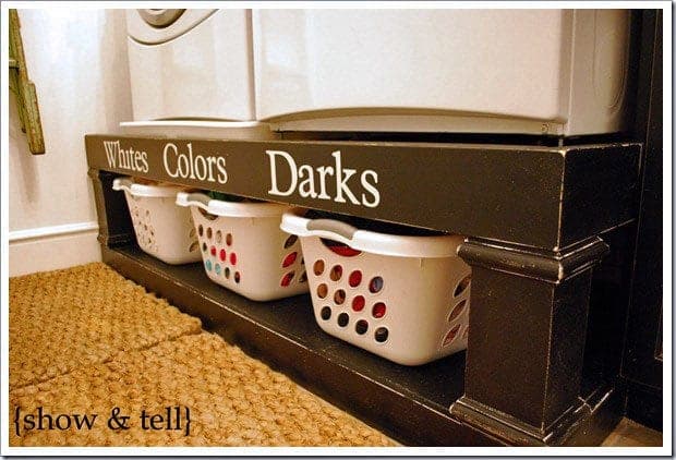 Washer and dryer raised on a farmhouse-style wooden pedestal with basket shelf below