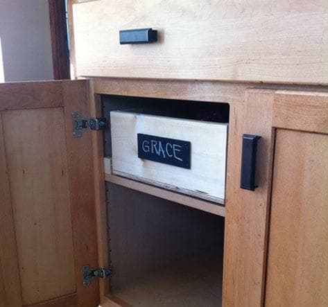 Wooden pull-out tray organizer on slides inside a cabinet