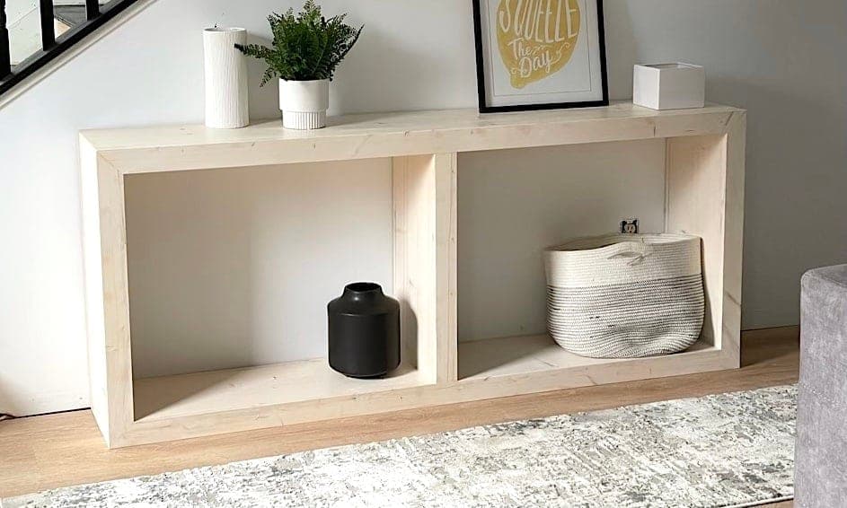 A long pine console table with mitered waterfall corners and two open shelf bays