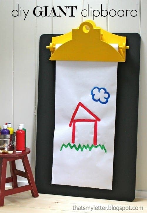 Oversized wall-mounted chalkboard shaped like a clipboard with a working wood dowel clip