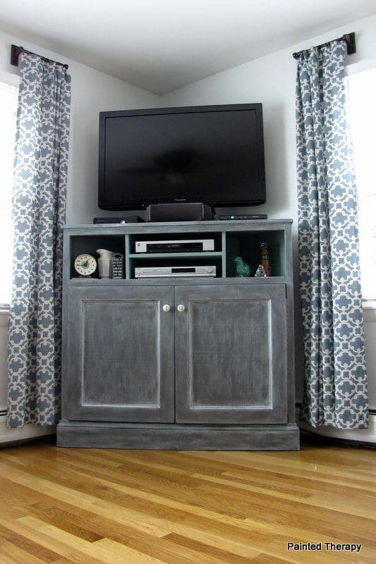 Tall corner media console with open component shelves above and a doored cabinet below