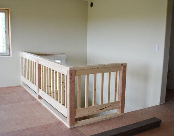 A wood deck handrail with 4x4 posts and evenly spaced 2x2 balusters
