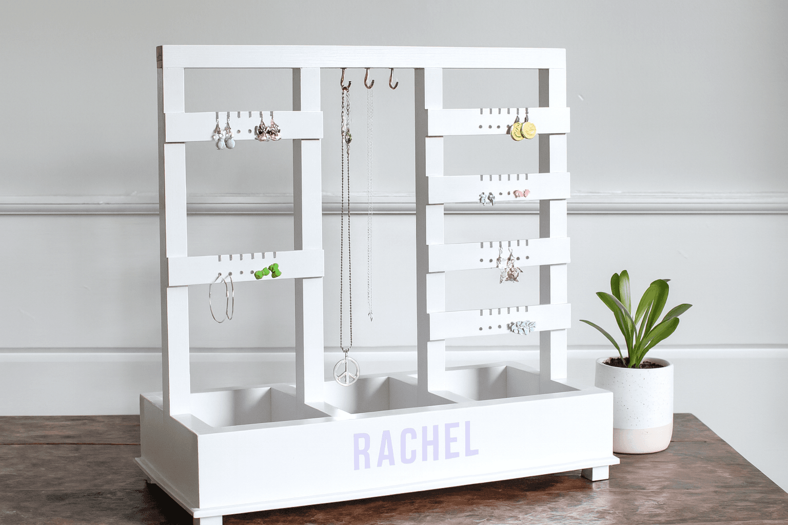 A small standing jewelry holder with three legs and a plywood base