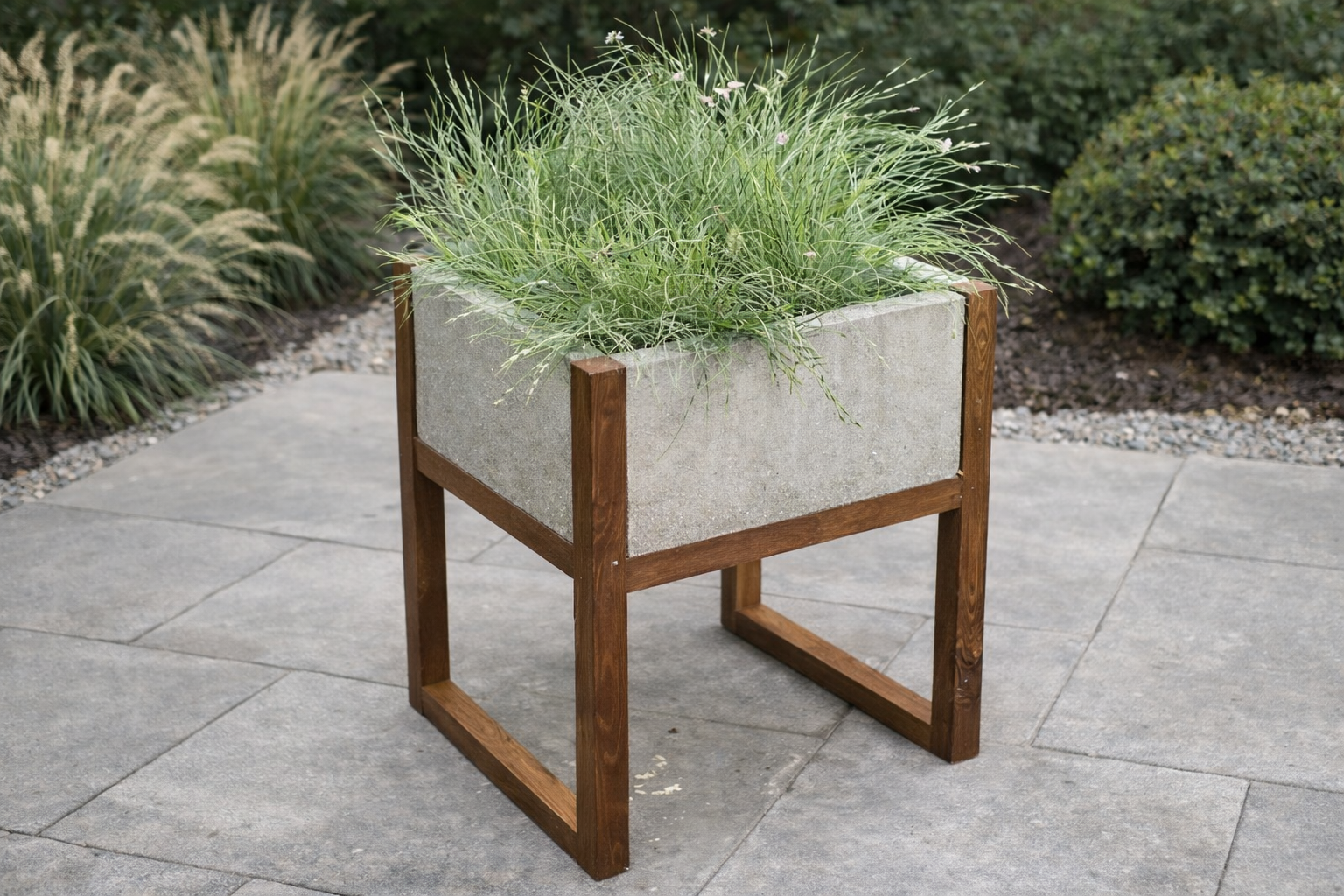 A modern planter box made from a cedar frame holding four concrete cap blocks as walls