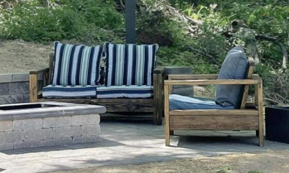 Outdoor wooden loveseat with slat back and seat cushions