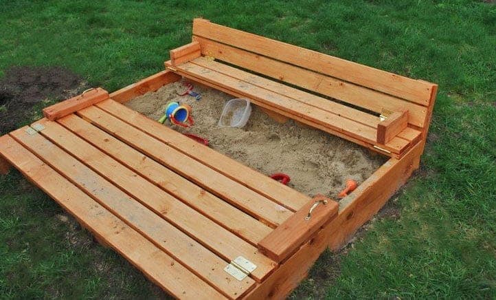 Wooden sandbox with lid panels folded open into two bench seats with backrests