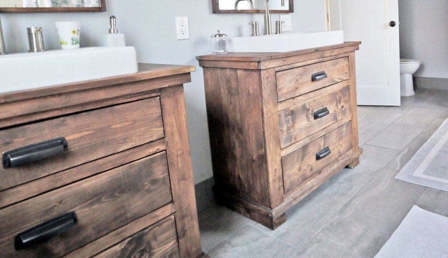 A rustic bathroom vanity with plank sides and three drawers with bin pulls