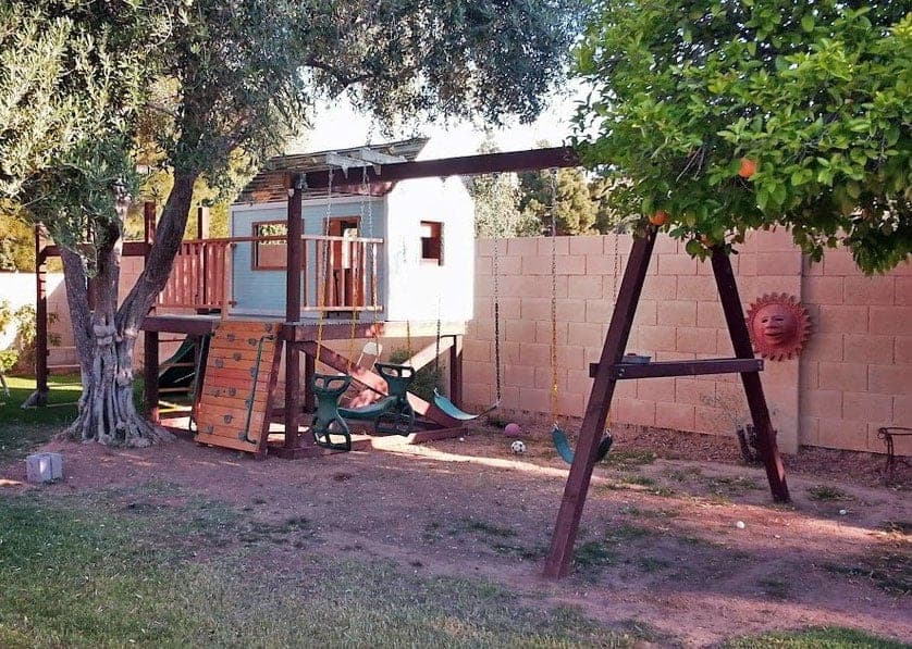 Bolted 4x4 swing set frame attached beside a playhouse porch
