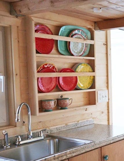 Wall-mounted wooden plate rack holding plates on edge