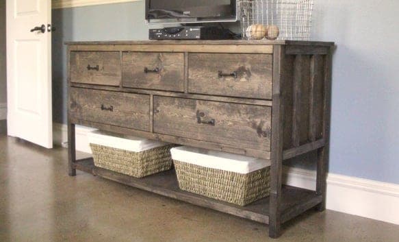 A five-drawer plywood dresser standing on an open bottom shelf