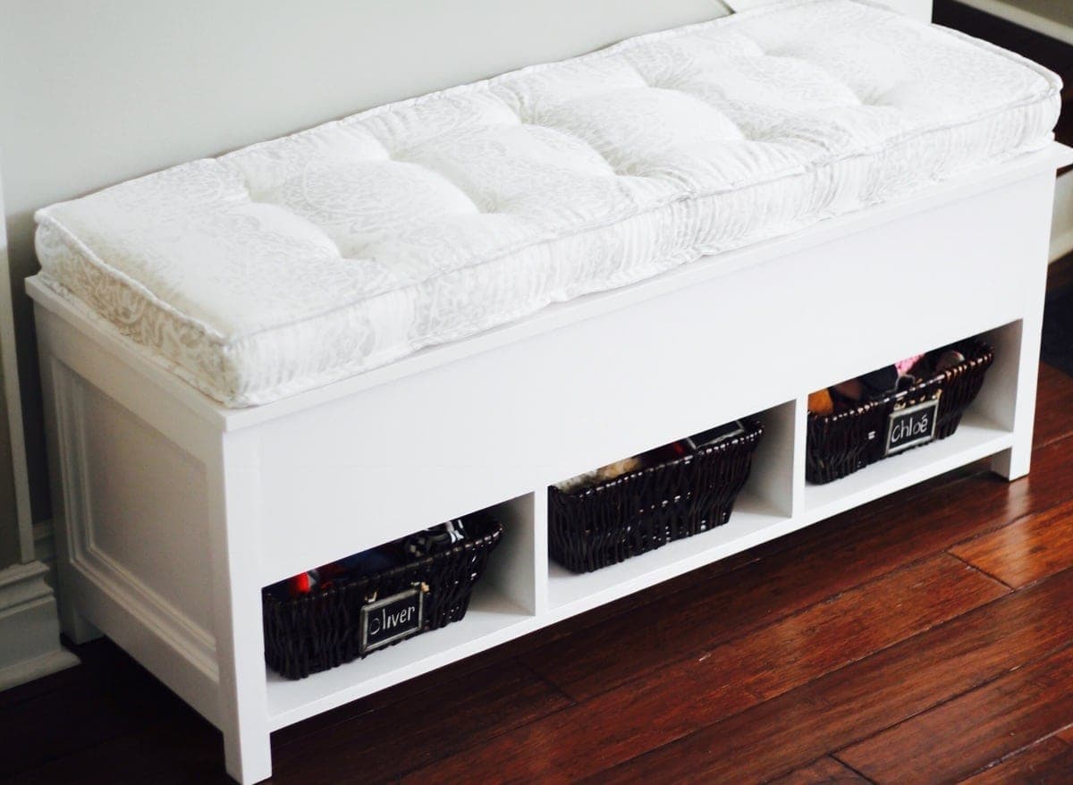 A storage bench with a hinged flip-top lid and an open divided cubby underneath
