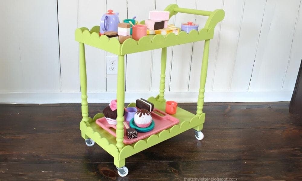 A small rolling kids tea cart with turned stair-spindle legs and a scalloped trim skirt