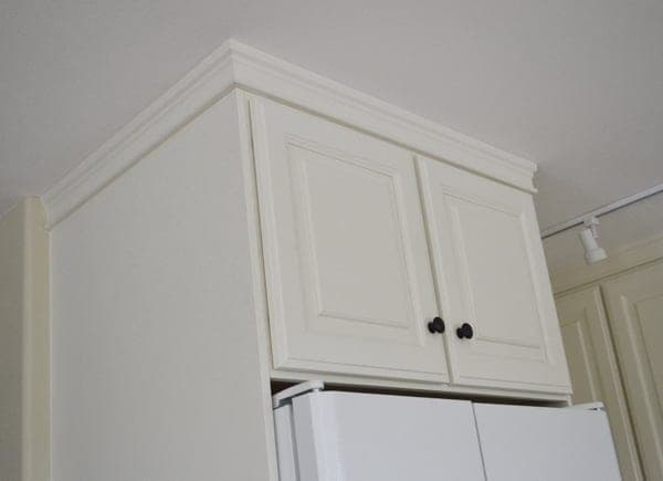 Shallow wall kitchen cabinet sized to fit above a refrigerator, with a face frame and two doors