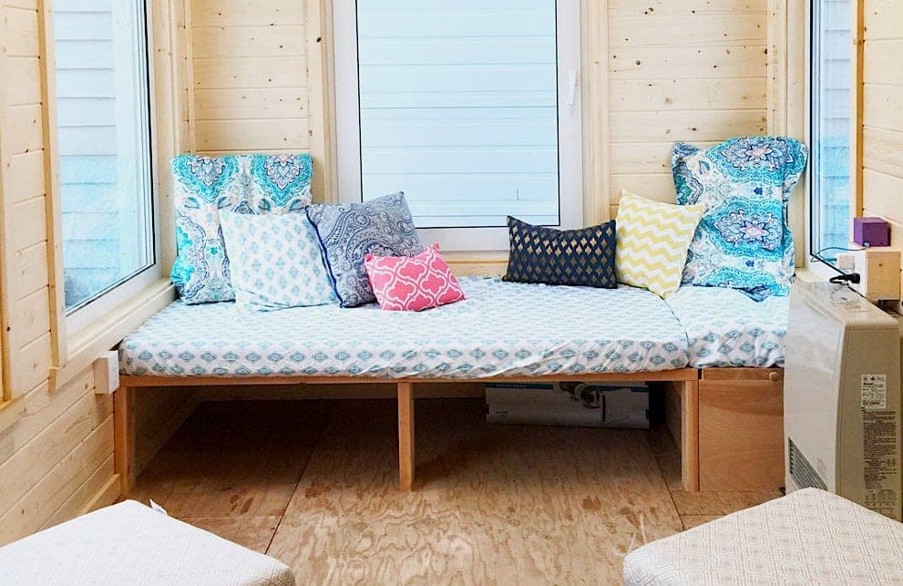 A built-in daybed frame made from 2x4s serving as a sofa in a nook