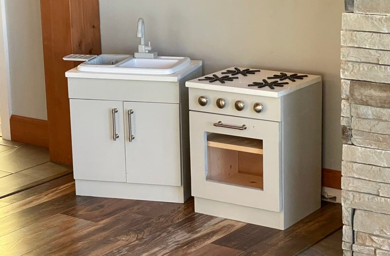 A matching toy kitchen sink and stove base cabinet, each with a hinged door