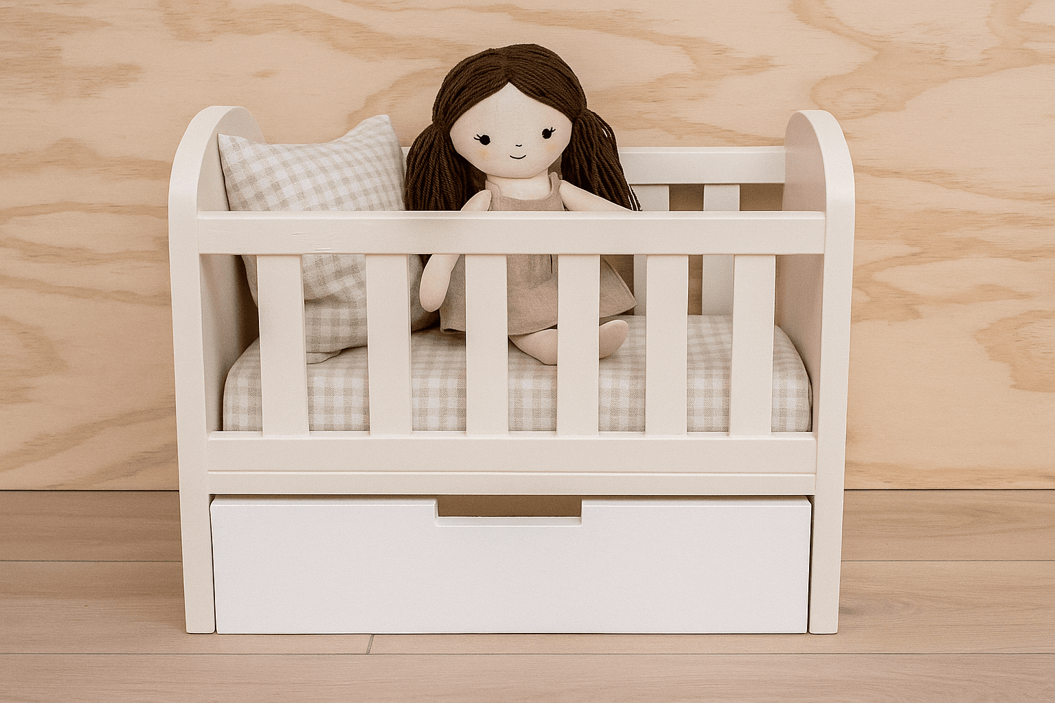 Small wooden doll crib with rounded end panels and a pull-out drawer