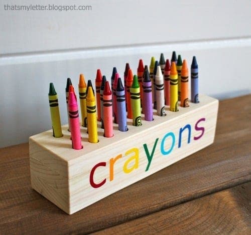Scrap wood block drilled with holes holding upright crayons