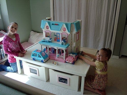 Kids' play table with raised side rails and two wheeled storage carts underneath