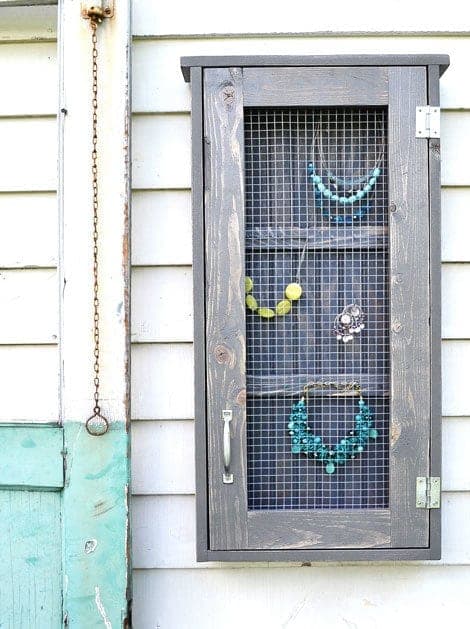 Small farmhouse-style wall cabinet with a hardware-cloth door front for hanging jewelry